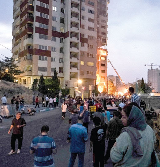 People watch a building that was hit after Israel’s attack in Tehran, Iran. June 13, 2025. For days, the fate of roughly 90 million Iranians has appeared to swing between war and peace as American and Iranian officials traded threats of attack and calls for diplomacy. (Arash Khamooshi/The New York Times)
