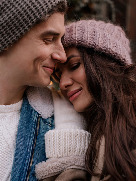 Close-up of couple touching foreheads in winter hats outside a West Village holiday-decorated boutique, NYC Christmas shoot