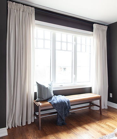 Upholstered bench next to large windows.