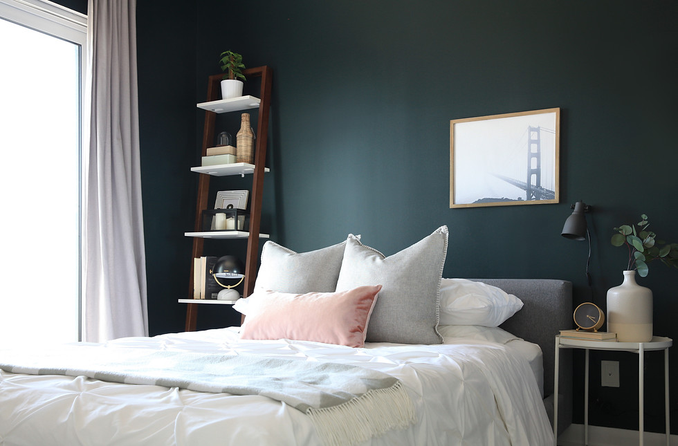Bedroom interior with a dark accent wall, light bedding, and a metal-framed bed.