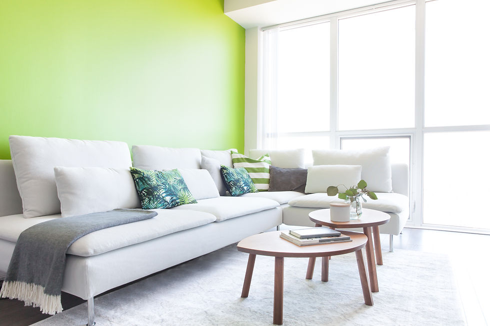 Modern living room with a bright green accent wall, a large white sectional sofa with various pillows, and two tiered, round