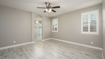 Bedroom with ceiling fan and closed shutters in a bright, modern scene.