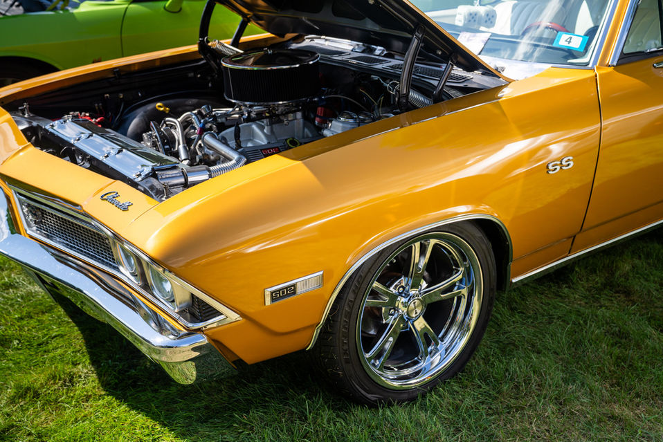 Vintage orange car with hood open, displaying engine.