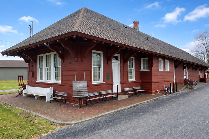 Historic red railroad depot under blue sky.png
