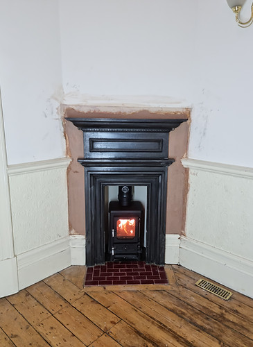 Black stove carefully fitted within a traditional painted fireplace
