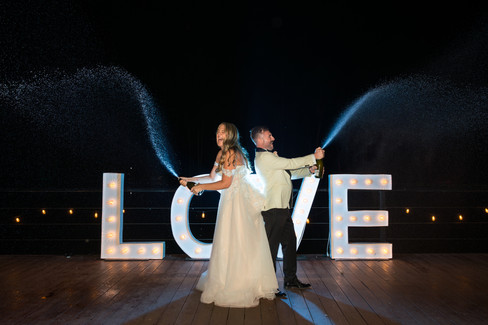 Champagne exploding into the air as the bride and groom celebrate together.