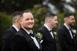 Groom looking at the camera and smiling whilst waiting for his bride
