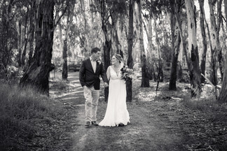 bride and groom walking hand in hand in forrest