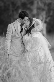 Bride and groom embracing with rolling hills behind them at sunset