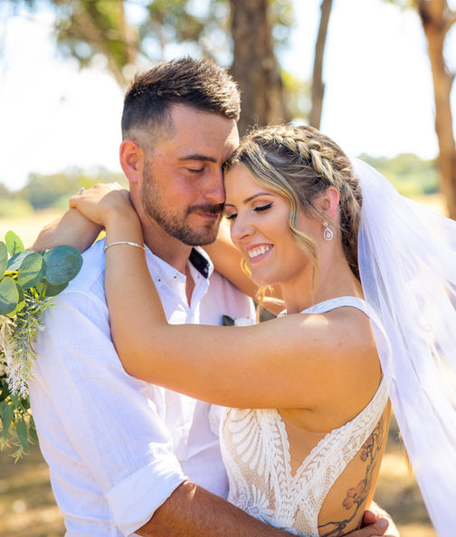 Bride and groom in each others arms at sunset