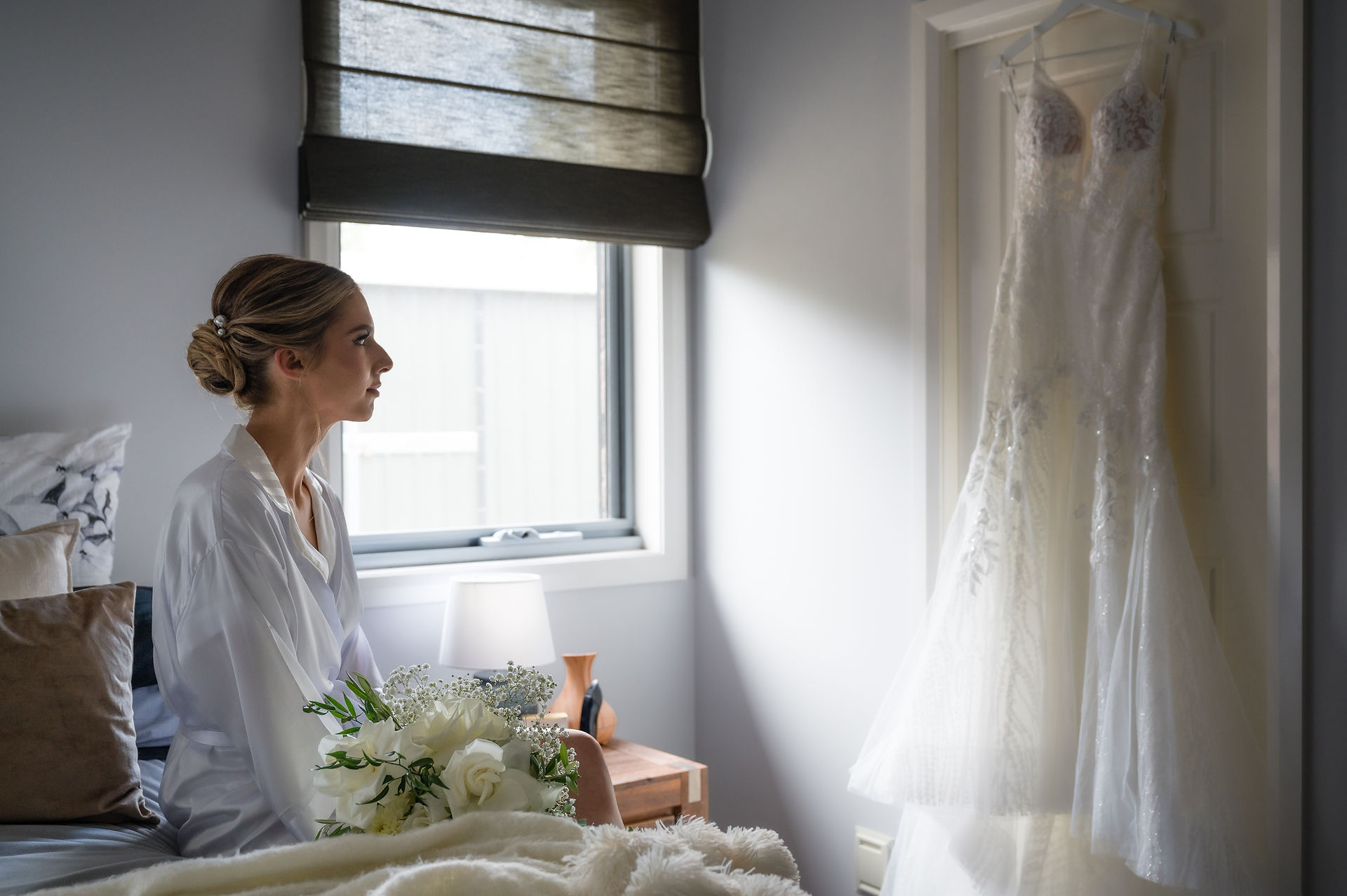 bride sitting on her bed looking at her dress