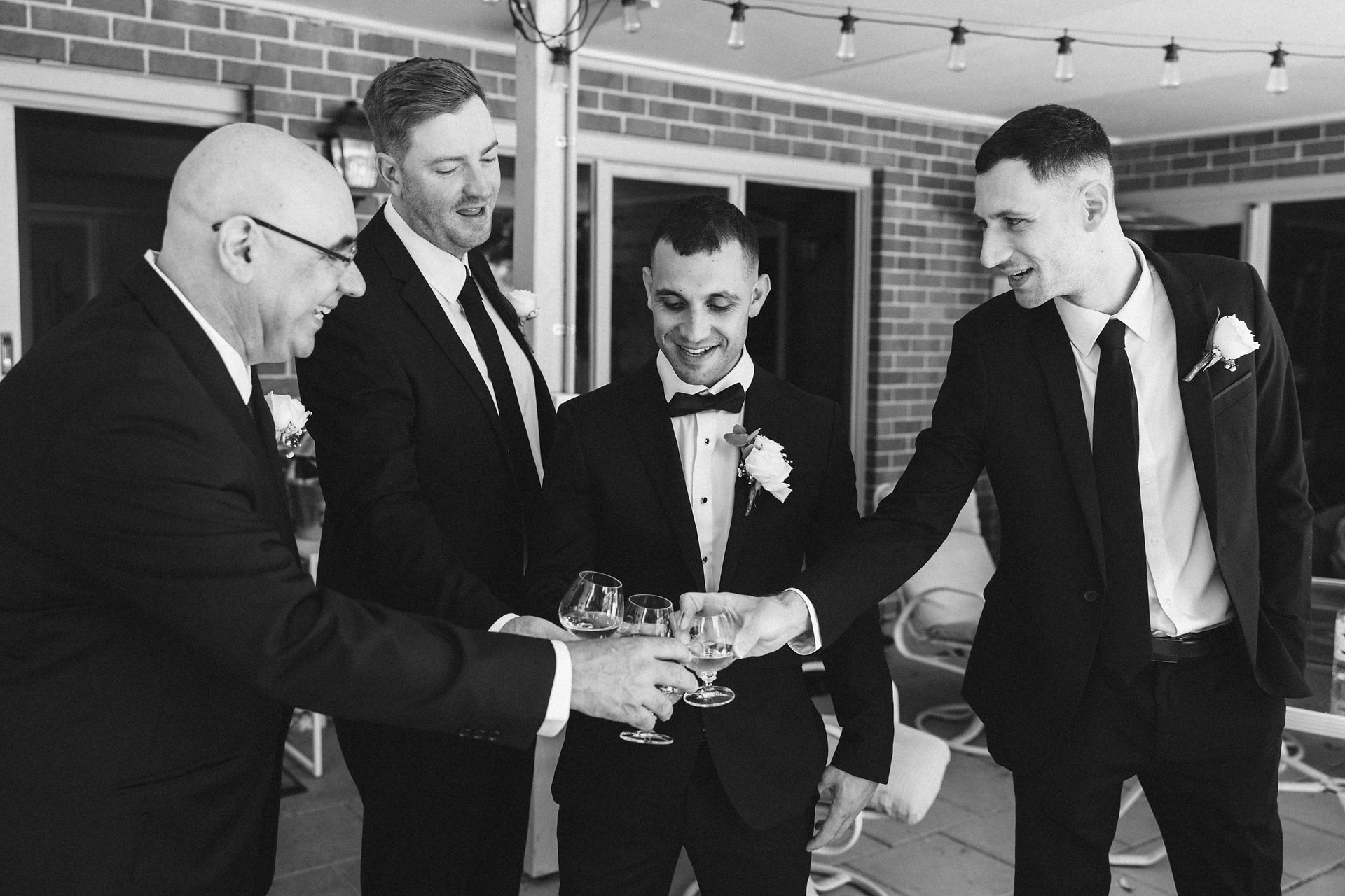 Groom and groomsmen sharing a drink while getting ready on the morning of a Melbourne wedding