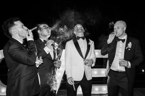 groomsmen sharing laughter while relaxing outdoors at night.