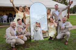 Bridal party gathering around mirror chearing bride and groom kissing at DV Cider