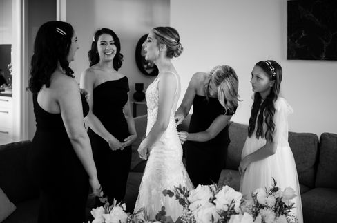 bridesmaids helping bride into her dress