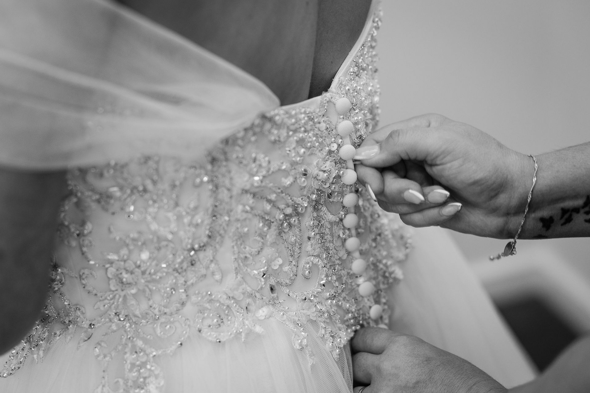 Bridesmaids assisting bride with dress buttons