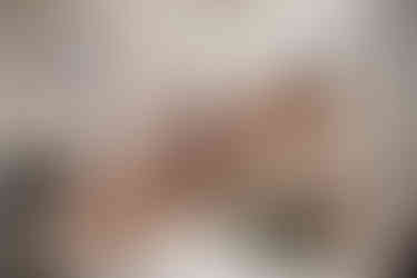 bride having pillow fight with bridesmaids on bed