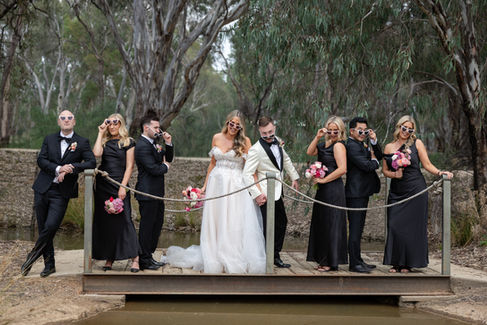 Bride and groom celebrating with their bridal party beside the manicured grounds.