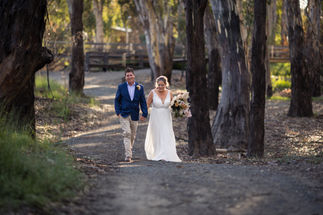 bride and groom walking hand in hand in forrest