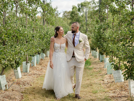 Bride and groom walking hand-in-hand along the orchard path at DV Cider during sunset.