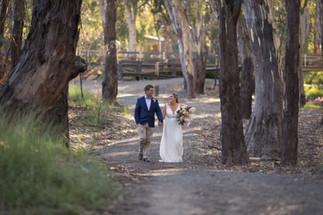 bride and groom walking hand in hand in forrest