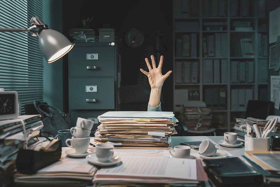 Hand reaching up from a messy desk buried in papers, needing admin support