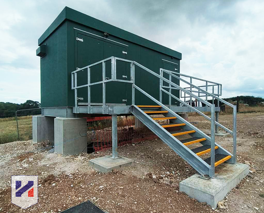 Green GRP substation kiosk and the access platform in front of it.