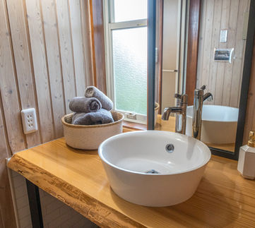 A bathroom with a round sink and wooden counter.