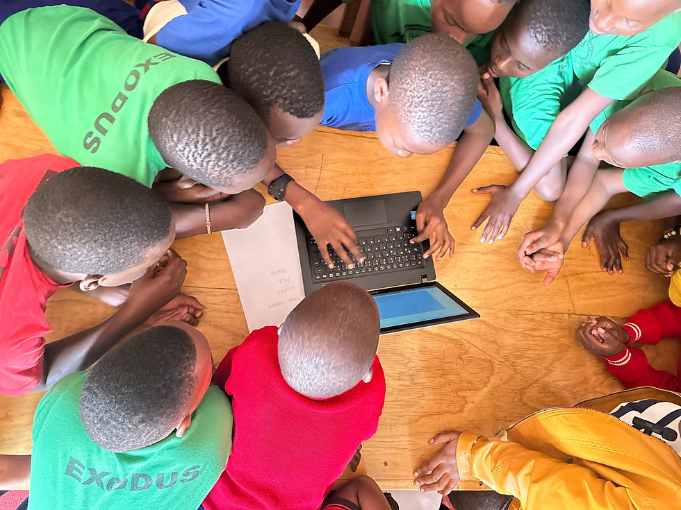 Students gather eagerly around a shared laptop, collaborating on a project at Saving Arms Primary School.
