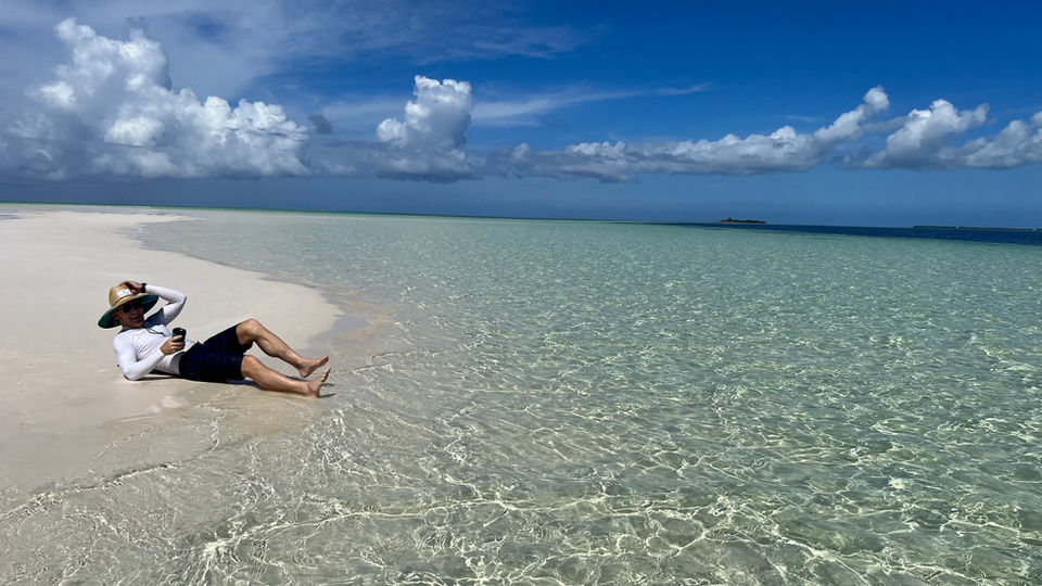 A person lying on a sandbar in the Bahamas