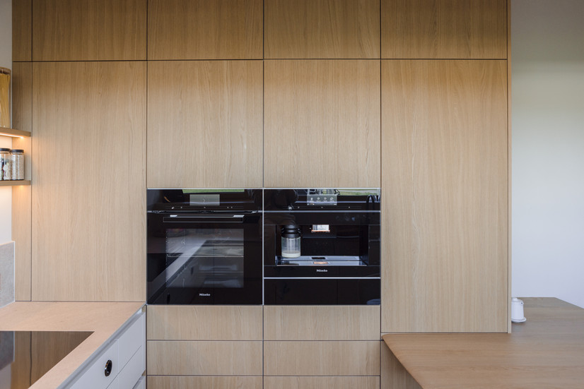 Moderne Küche mit integrierten Geräten und eleganten Holzfronten in klarer Linienführung.