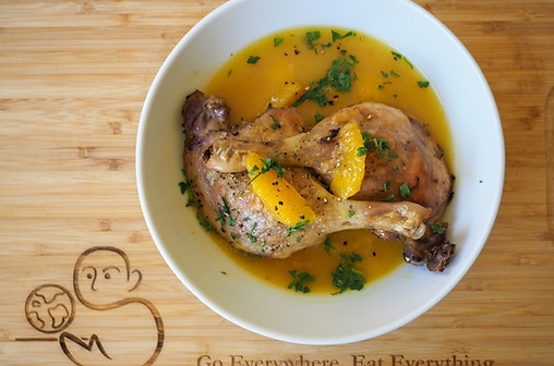 Top view of a bowl of Duck a l'Orange by Simon Majumdar. Text, "Go Everywhere, Eat Everything"