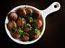 A small skillet with baby bella mushrooms garnished with greens