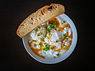 A bowl of poached eggs in yogurt and a side of long bread