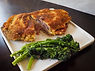 A plate with a sliced breaded meat with a side of broccolini