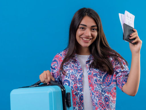 A girl holding suitcase in one hand and ticket and passport in the other hand