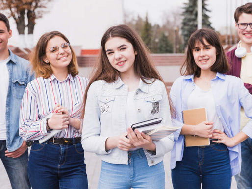 a bunch of students holding books in front of a college
