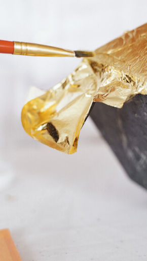 A man brushing through gold paper on a rock