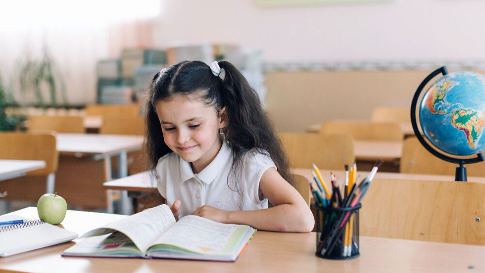 A child learning in a classroom with a book on a wooden table