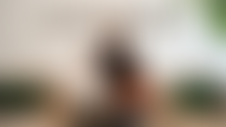 Drei Frauen sitzen und stehen vor einem hellen Hintergrund auf einem Sofa. Hinter ihnen ist das Logo „STADT.LAND.NETZ“ an der Wand zu sehen. Zwei Frauen sitzen nebeneinander auf dem Sofa, eine trägt ein helles Oberteil und dunkle Hose, die andere eine orangefarbene Jacke. Eine dritte Frau steht hinter ihnen, trägt einen schwarzen Rollkragenpullover und schaut in die Kamera. Links und rechts liegen grüne Kissen auf dem Sofa, daneben ist eine große Zimmerpflanze zu sehen.