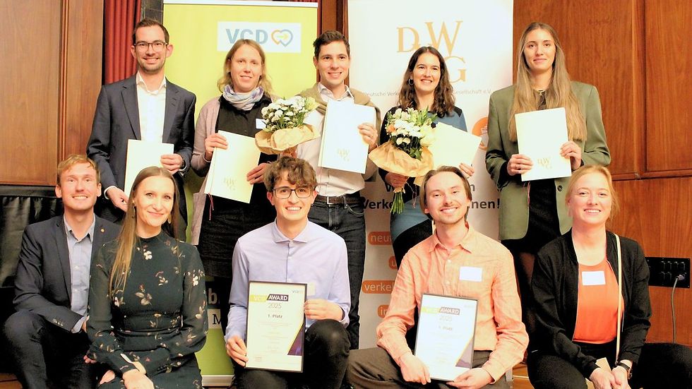 Gruppenfoto der Preisträger:innen der Shaping Mobility Awards 2025 mit den Initiator:innen und Stifter:innen. Zehn Personen posieren mit Urkunden und Blumen vor den Roll-ups von VCD und DVWG. Vorne links sitzt Dr. Ines Kawgan-Kagan in einem dunkelgrünen Kleid. Die ausgezeichneten Nachwuchswissenschaftler:innen halten ihre Urkunden und Preisunterlagen in den Händen. Das Foto entstand im Rahmen der Preisverleihung der Shaping Mobility Awards.