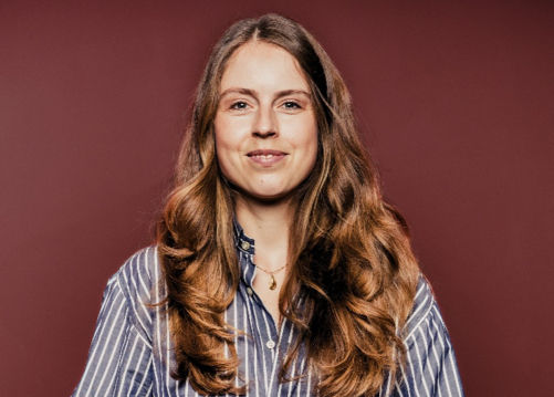 Carolin Bauder vom Institut für Mobilität der Universität St. Gallen vor dunkelrotem Hintergrund.