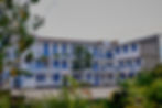 Bâtiment 2 du campus de Goma de l'Université Internationale de Nouvelles Technologies (UNITECH), entouré de verdure avec un terrain de basket-ball.
