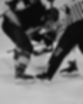Two hockey players competing for the puck during a game, with a referee watching closely in the background.