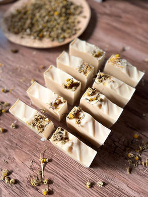 yellow camomile soap standing ona rustic background table soap has dried camomiles on it