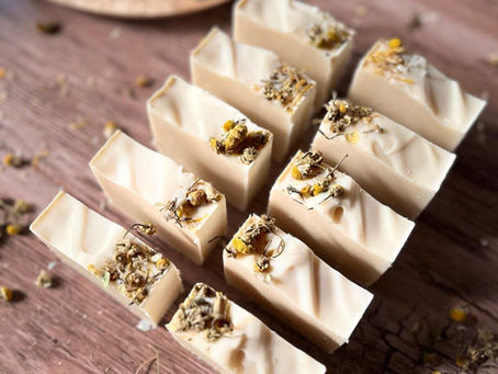 yellow camomile soap standing ona rustic background table soap has dried camomiles on it