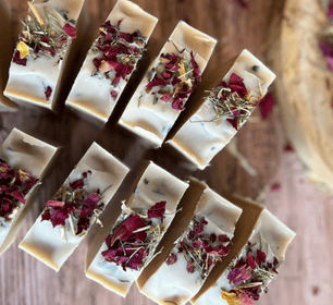 beige colour soaps with dried roses on them standing on rustic brown colour table