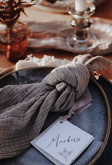 Ein Namenskärtchen im Boho-Stil liegt auf einem festliche gedeckten Hochzeitstisch