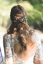 Eine Braut im Brautkleid von hinten mit Brautfrisur und Blumenschmuck