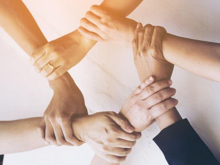Hands of diverse team members joined together in unity, symbolizing strong workplace relationships